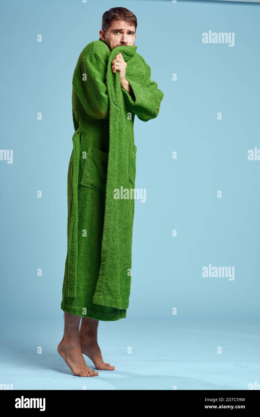 a man in a green robe in full growth on a blue background barefoot