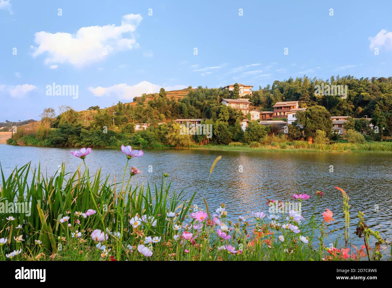 The idyllic mountain tranditional Chinese village by river on a beautiful summer afteroon with blossoming trees and flowers in the south of China Stock Photo