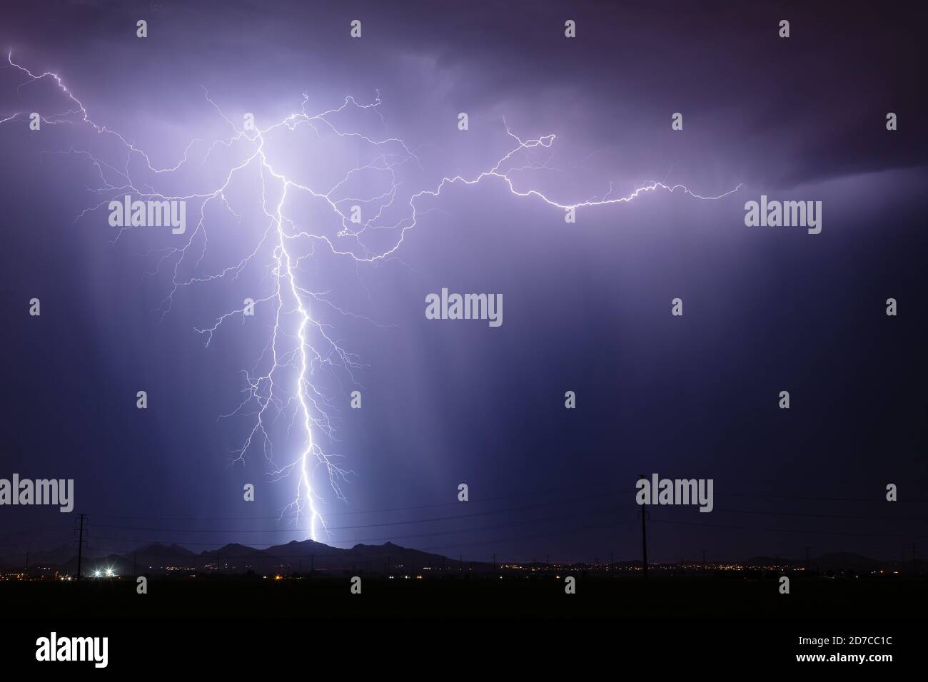 A lightning bolt strikes from a storm in the night sky over Phoenix, Arizona Stock Photo