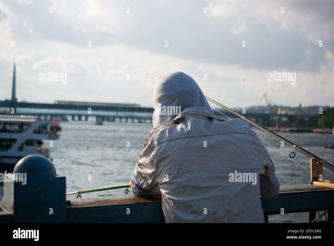 Closeup shot from behind of a man fishing from a bridge Stock Photo - Alamy