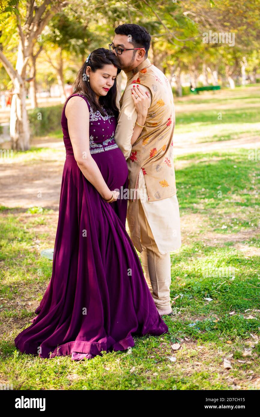 Young asian indian pregnant woman with her husband wearing traditional  outfit standing in park or garden copy space to write text Stock Photo -  Alamy