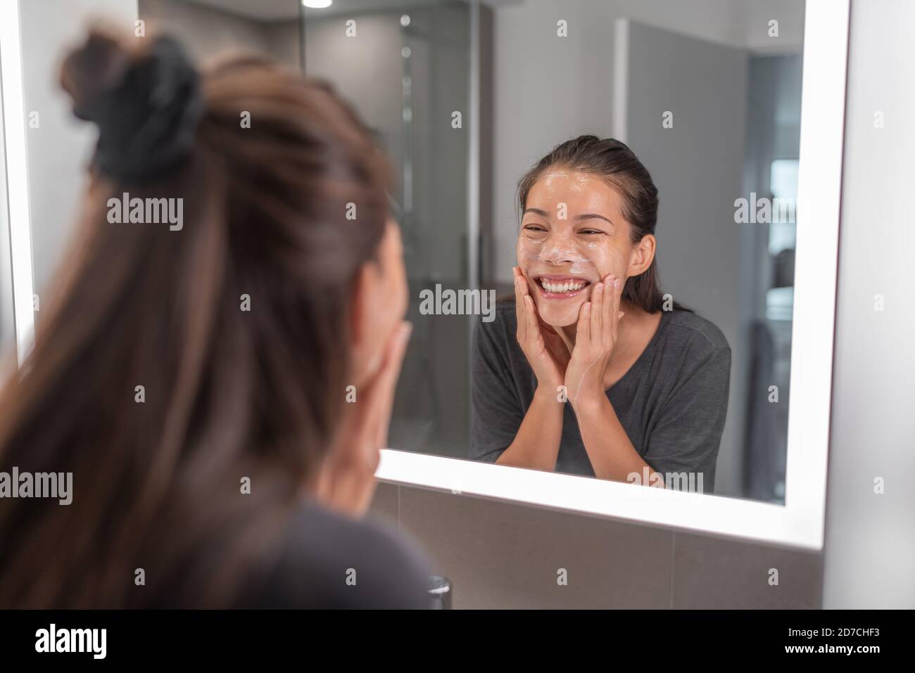 Face wash young Asian woman washing using facial scrub exfoliating skin cleansing of dead cells and oil for black pores clear skincare treatment Stock Photo