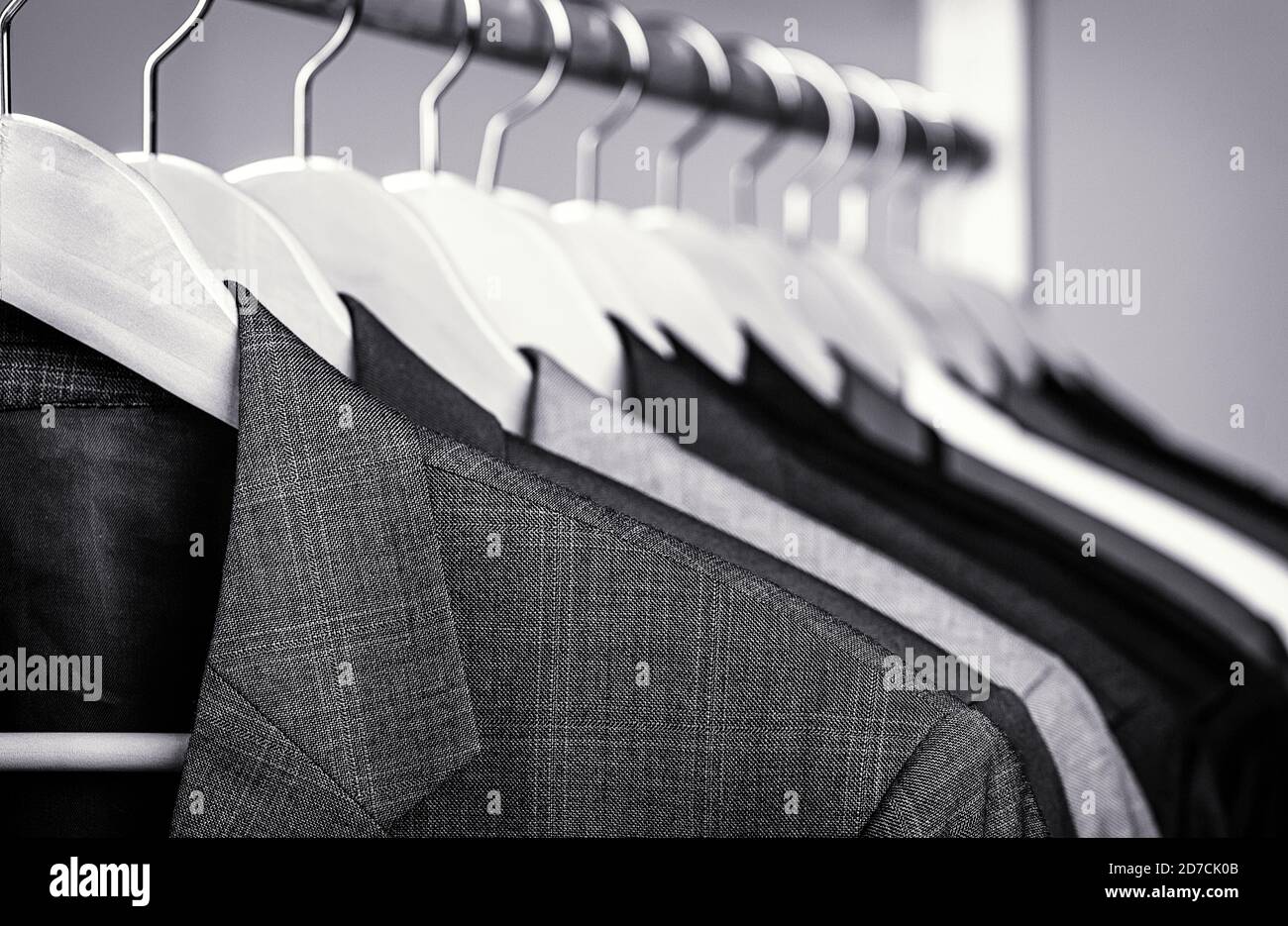 Mens suits in different colors hanging on hanger in a retail clothes