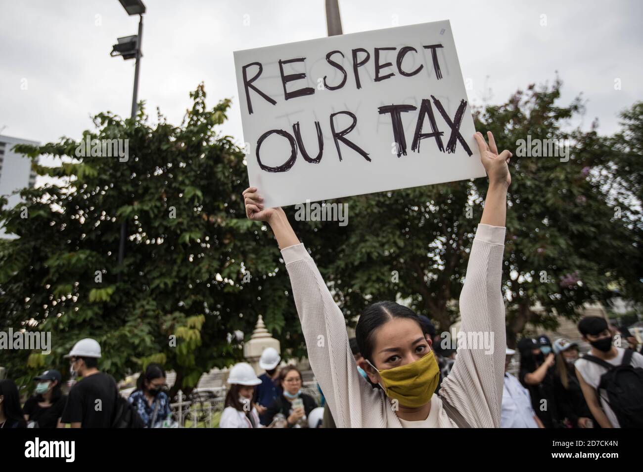 A pro-democracy protester holds a plaacrd saying 'Respect Our Tax' during an anti-government demonstration in the Thai Capital. Thousands of pro-democracy protesters took the streets at Victory Monument demanding the resignation of Thailand Prime Minister and the reform of the monarchy for the seventh day after a ‘severe state of emergency' declared by Prime Minister Prayut Chan-o-cha. The protesters marched from Victory Monument to Government House and delivered a letter to Prime Minister Prayut Chan-o-cha asking him to resign before 3 days. The protest ended peacefully. Stock Photo