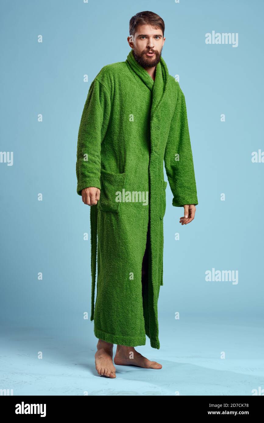 a man in a green robe in full growth on a blue background barefoot