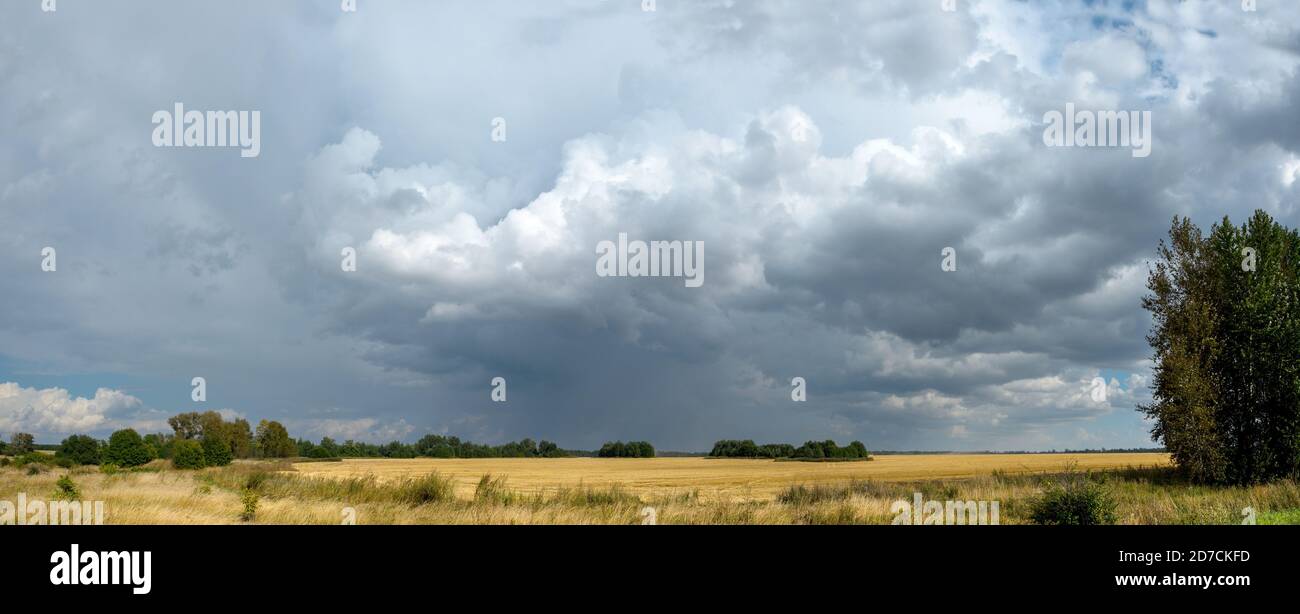 Rural panoramic landscape with dark stormy clouds in dramatic sky over ...
