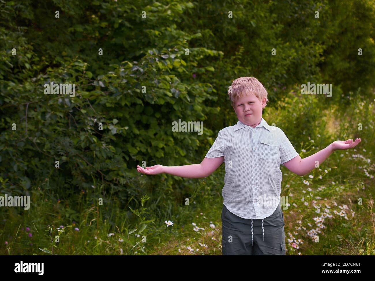 A confused boy throws up his hands on a walk in the Park in the summer Stock Photo