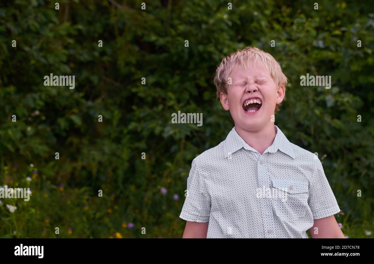 Angry boy screams on a walk in the Park in the summer Stock Photo