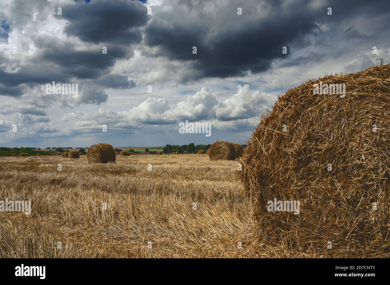 Dark stormy clouds over the farm field with haystacks Stock Photo - Alamy