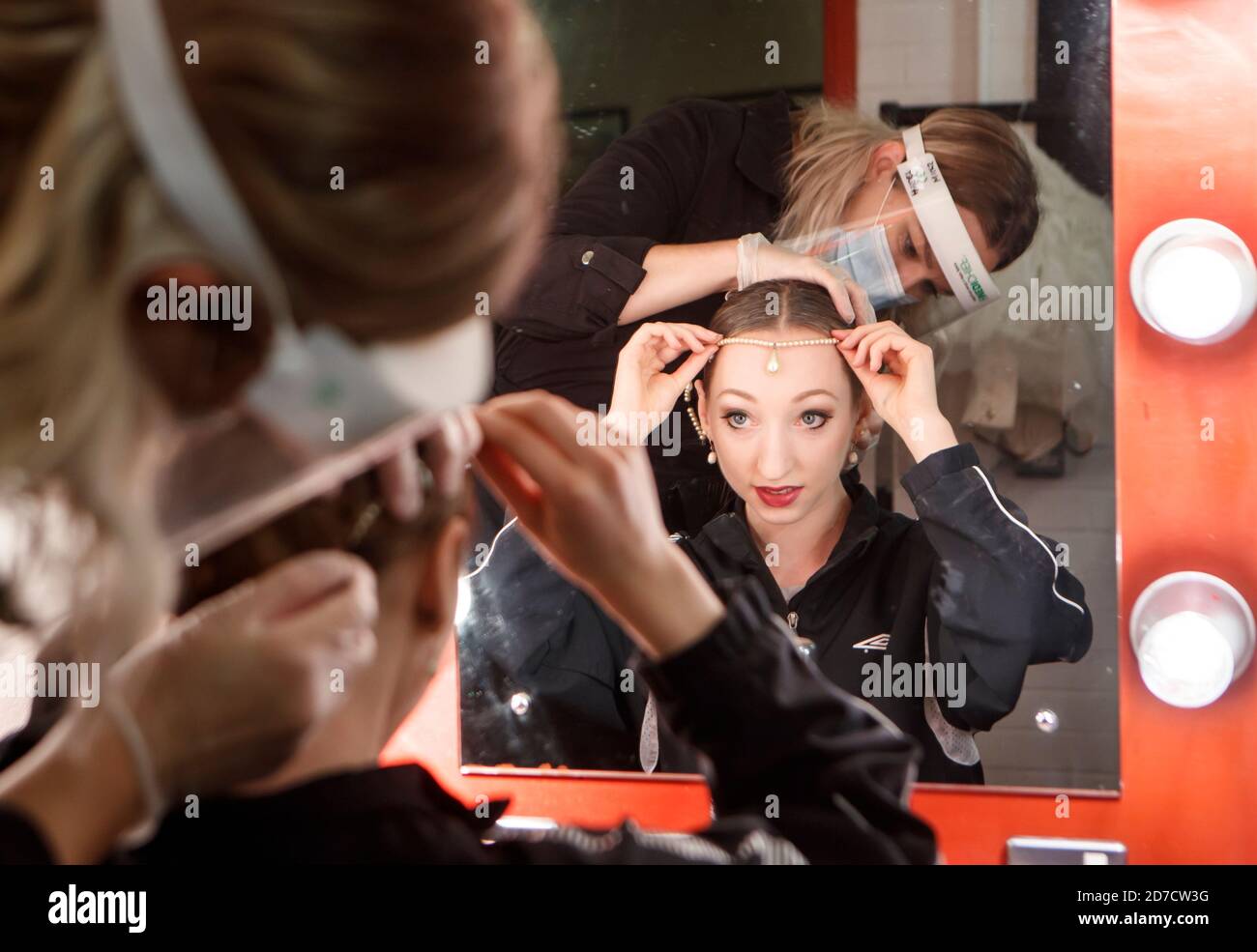 A member of the back stage staff wears PPE as she helps a ballerina from Northern Ballet