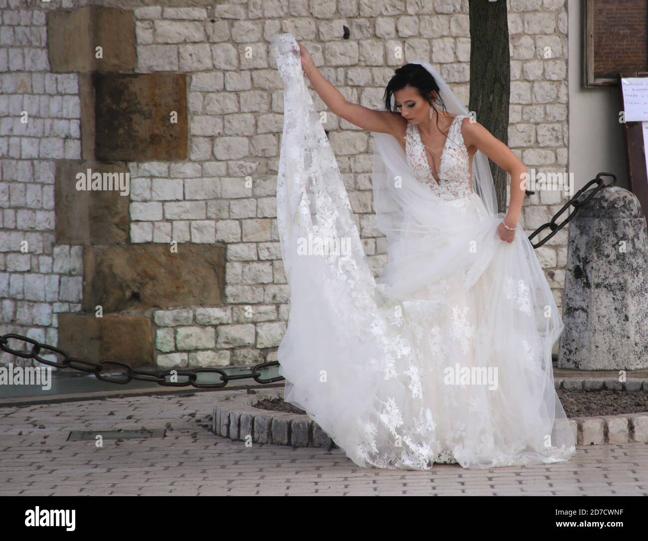 Cracow. Krakow. Poland. Young woman wearing wedding gown preparing for photo session outdoors. Stock Photo