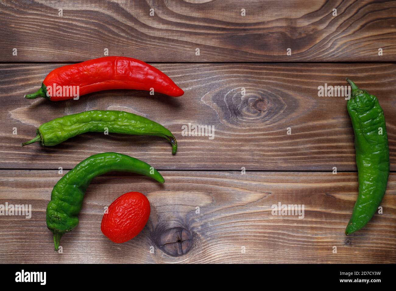 Shriveled stale tomatoes and peppers on a wooden background. Flat layout. Place to copy. Ugly food. Stock Photo