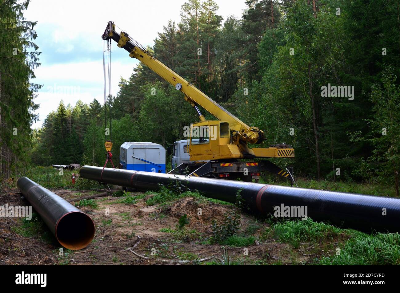 Crane lowers a section of pipe into a trench. Construction of gas