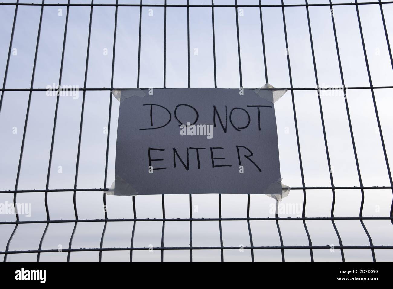 DO NOT ENTER text on the yellow plate on a mesh wire fence. Quarantine Area COVID-19. Outbreak of the coronavirus epidemic has led to the closure of b Stock Photo