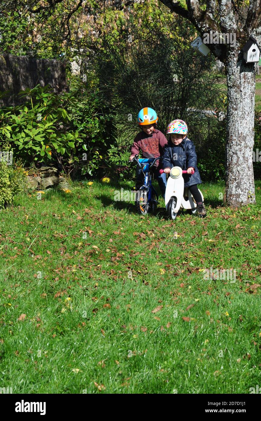 Brother and sister playing in the garden with her bike Stock Photo - Alamy