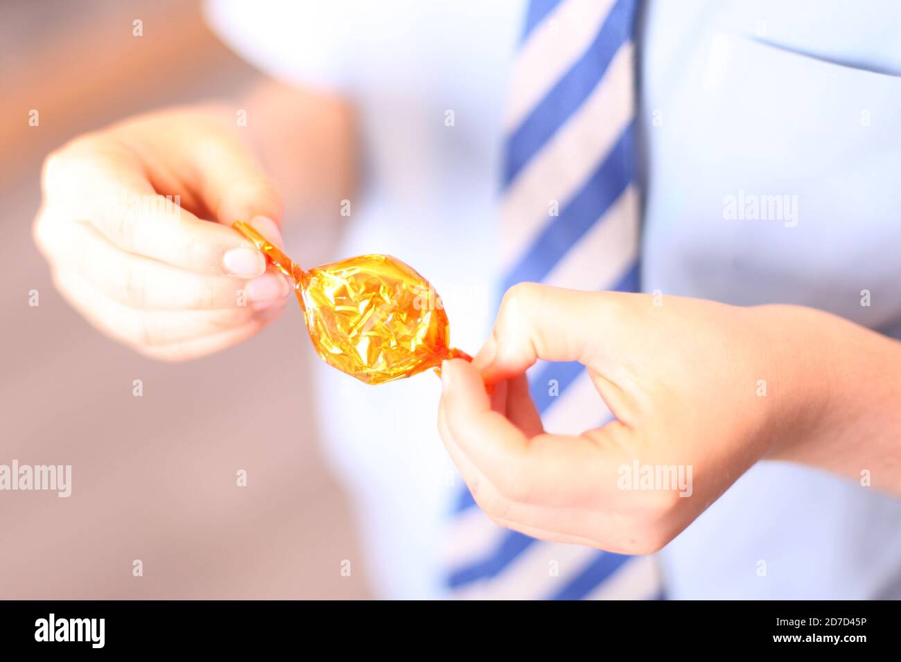 Child unwrapping Quality Street Toffee Penny wrapped sweet in wrapper, close up Stock Photo