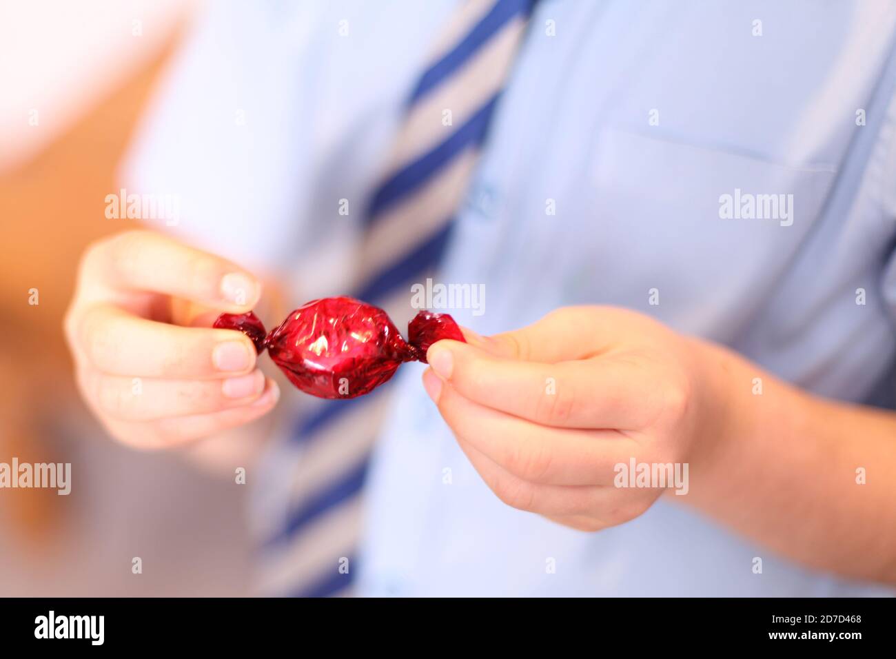 Child unwrapping Quality Street Strawberry Delight chocolate sweet wrapped in wrapper, close up Stock Photo