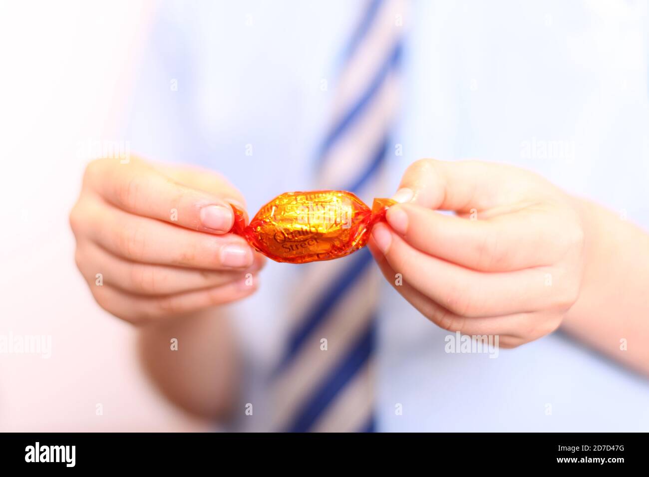 Child unwrapping Quality Street Orange Creme chocolate sweet wrapped in