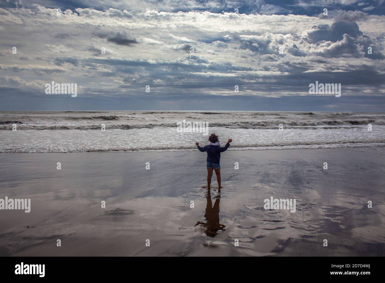 Lonely child at the sea during a stormy day. Stock Photo