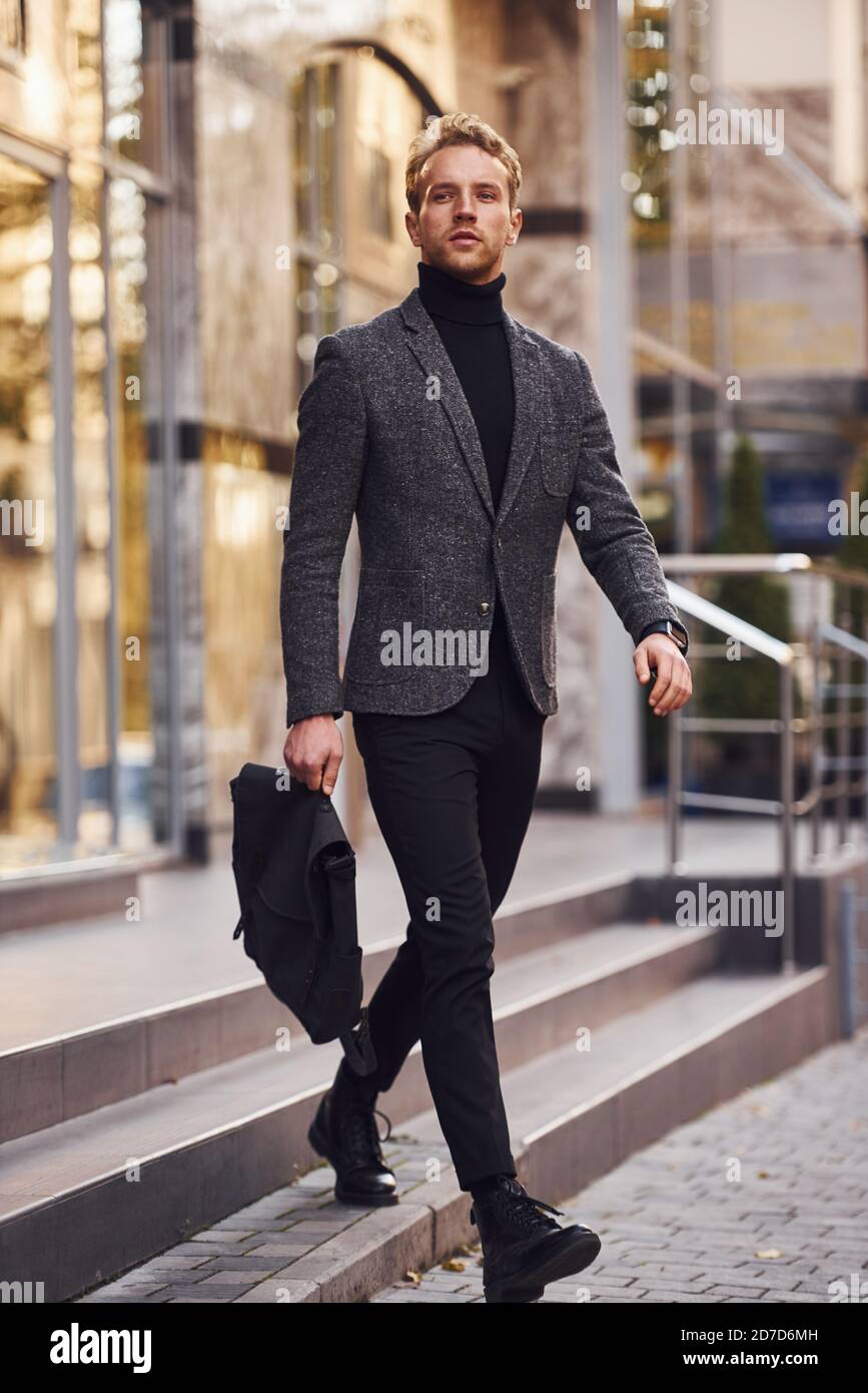 Man in elegant formal wear and with bag is outside against modern building  Stock Photo - Alamy