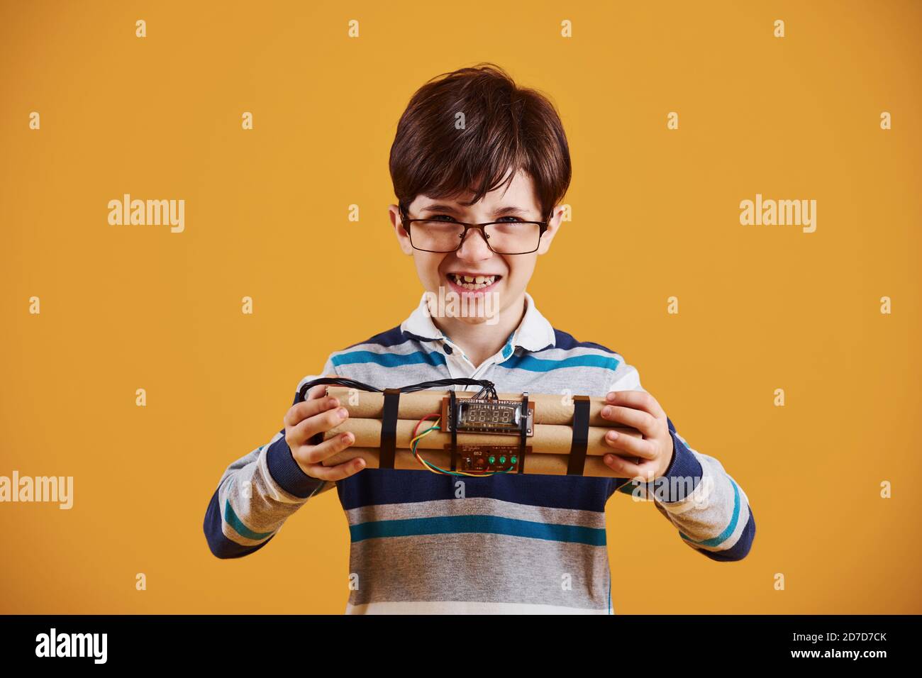 Little boy with explosive in the studio against yellow background Stock ...