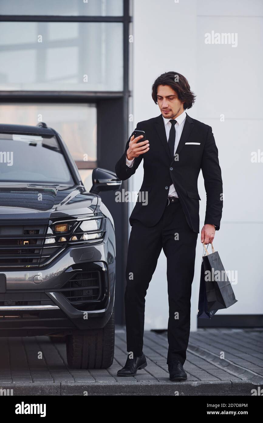 Portrait of handsome young businessman in black suit and tie outdoors ...