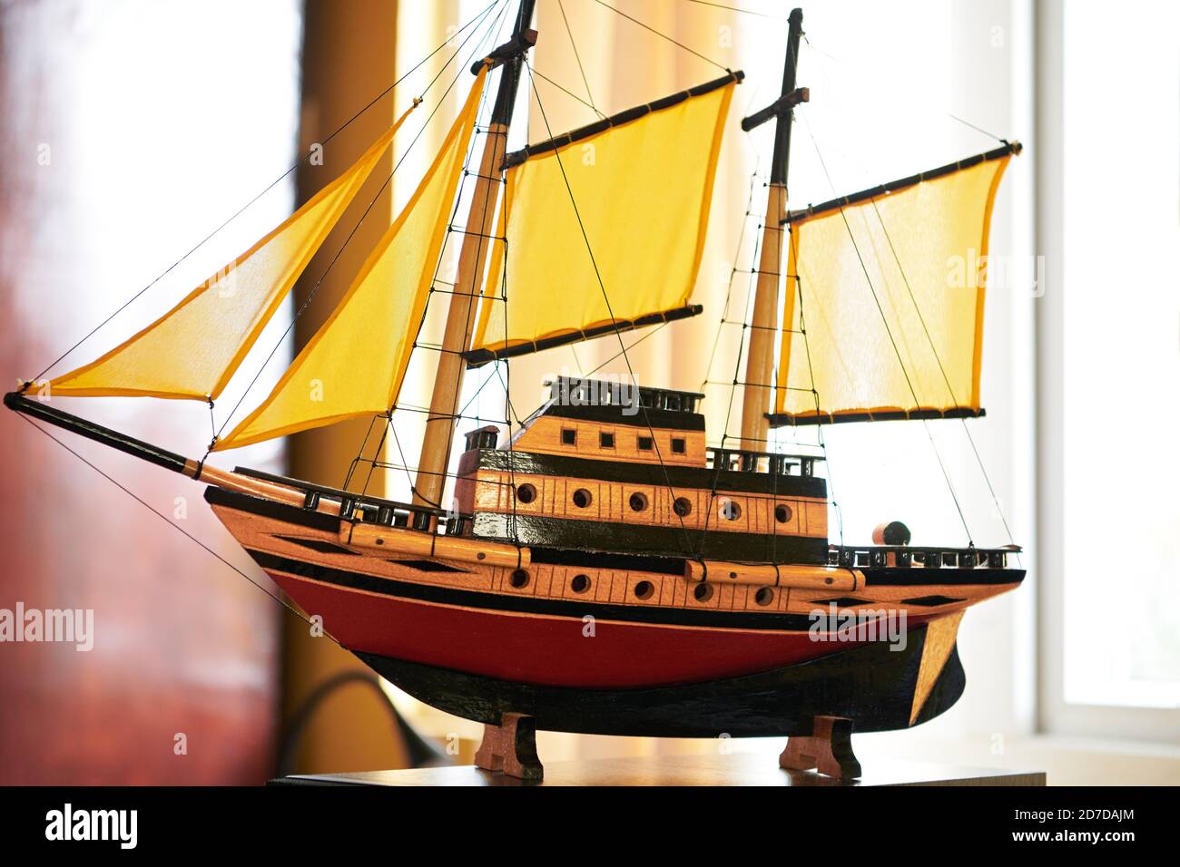 Close-up view of a miniature wooden sailboat with yellow sails, sold as souvenir in touristic places and souvenir shops around the world Stock Photo