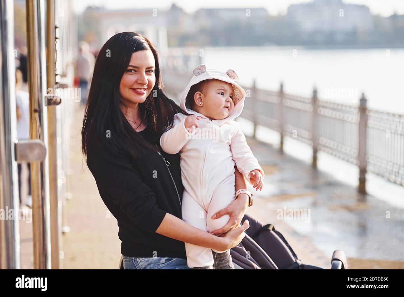 Mother with pram in casual clothes with her child is in the park Stock Photo