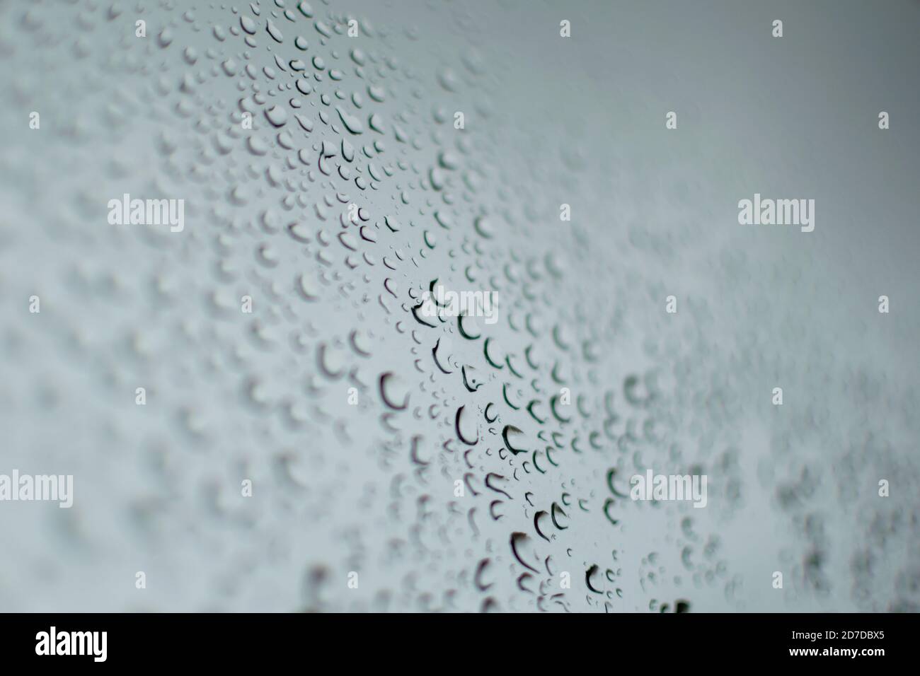 multiple rain drops on a grey window during a thunder storm Stock Photo