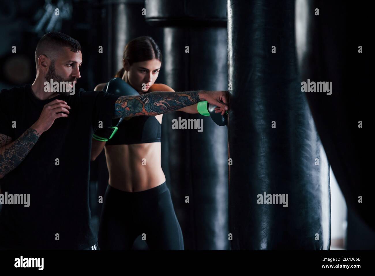 Young tattooed boxing coach teaches young woman in the gym Stock Photo