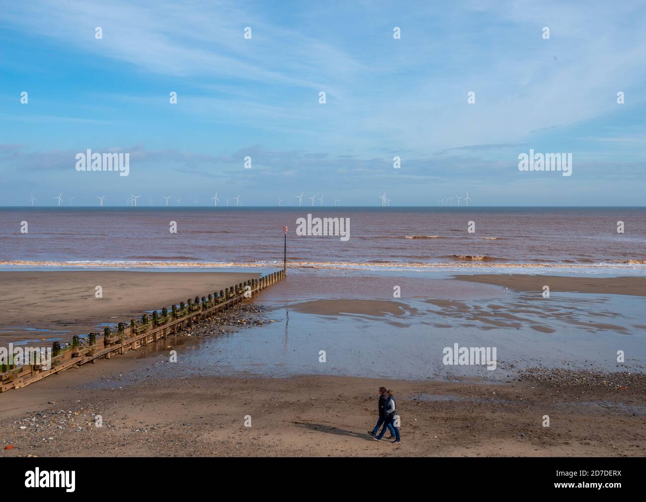 Withernsea, East Yorkshire, England, 20/10/2020 Couple walking along a cold beach with wind