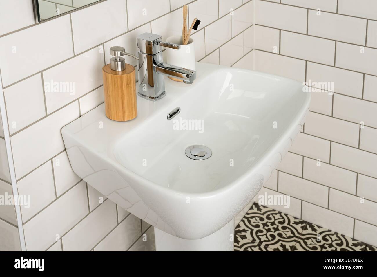 Bathroom sink and faucet with toothbrushes and soap dispenser Stock Photo -  Alamy