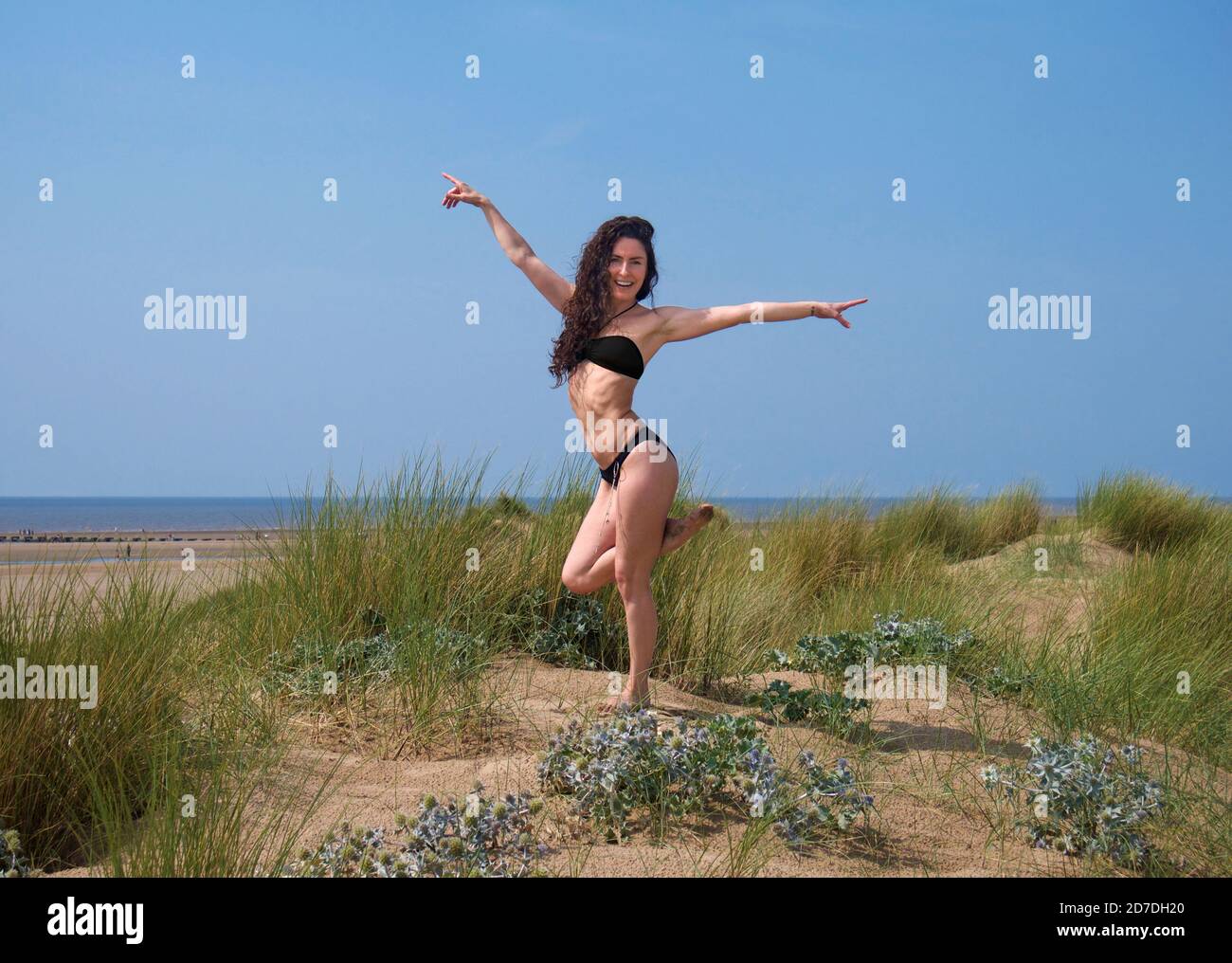 Mid-thirties woman in black bikini posing on sand dune Stock Photo