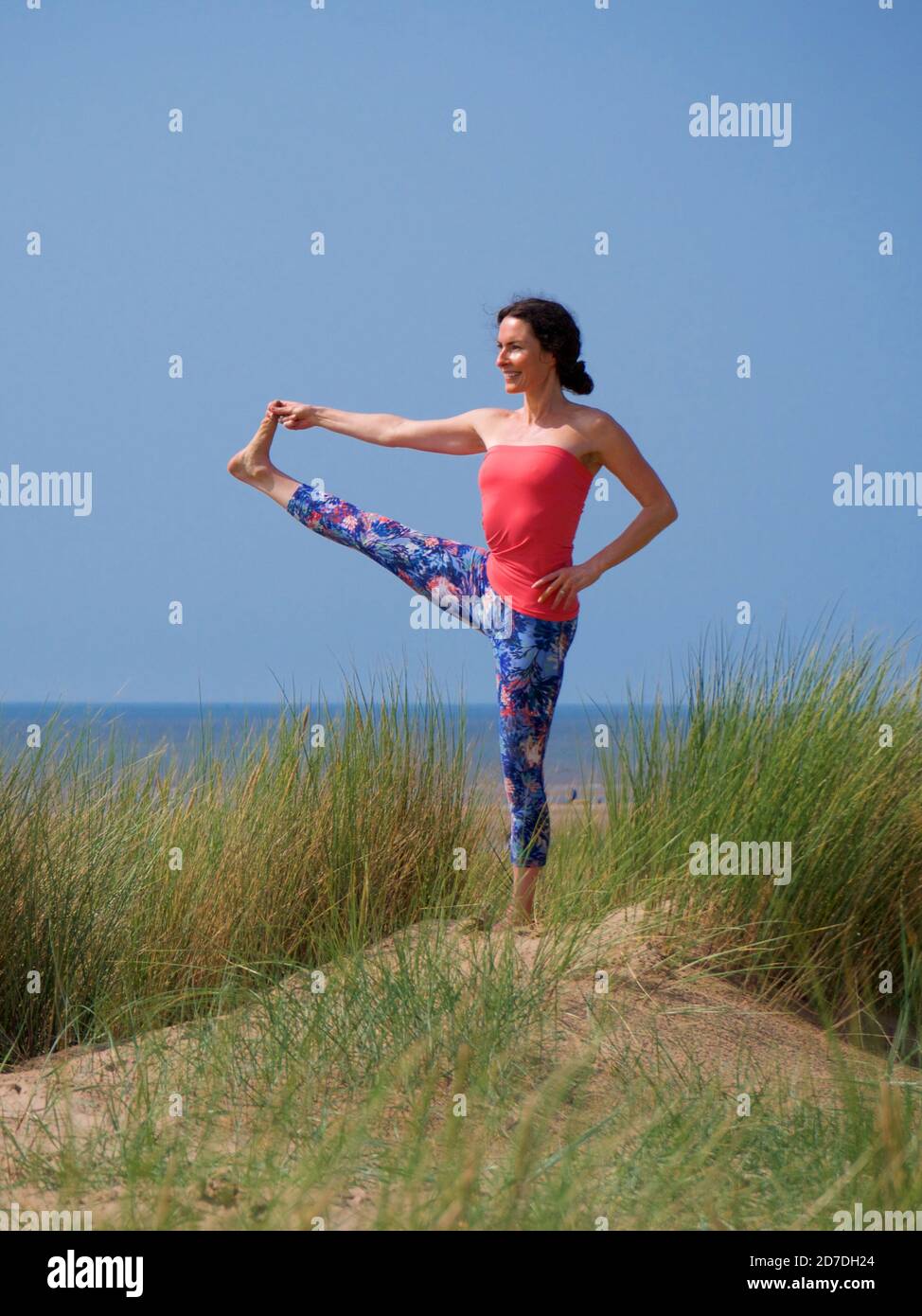 woman doing yoga pose on sand dune Stock Photo