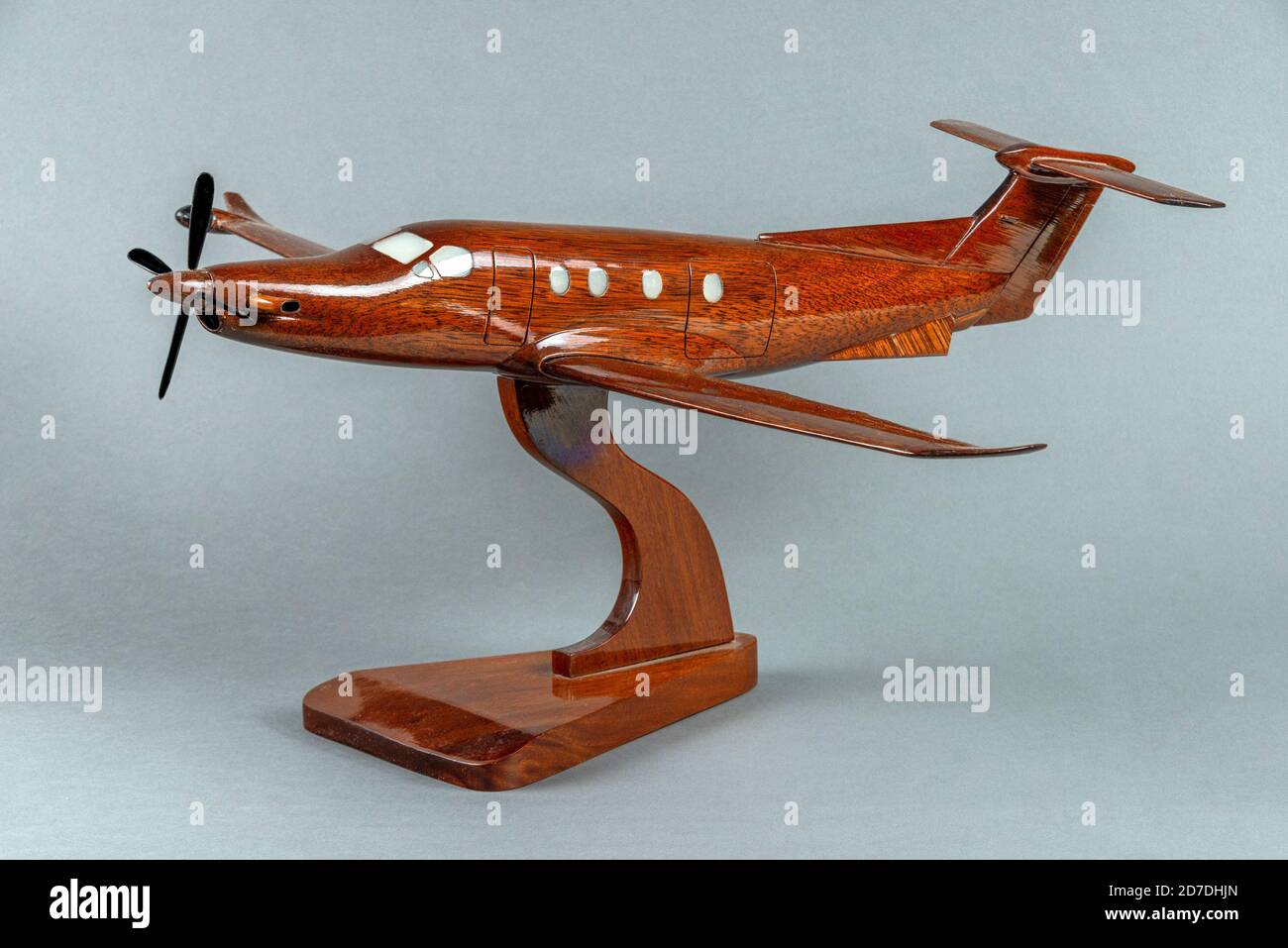 A three quarter side on view of a wooden, hand made model of a Pilatus PC12 aircraft on a stand. Stock Photo