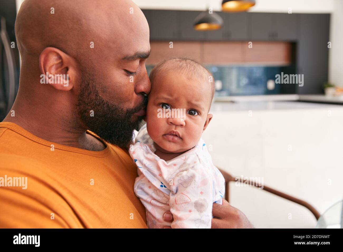 Smiling Stay At Home African American Father Cuddling And Playing With Baby Daughter Indoors At Home Stock Photo