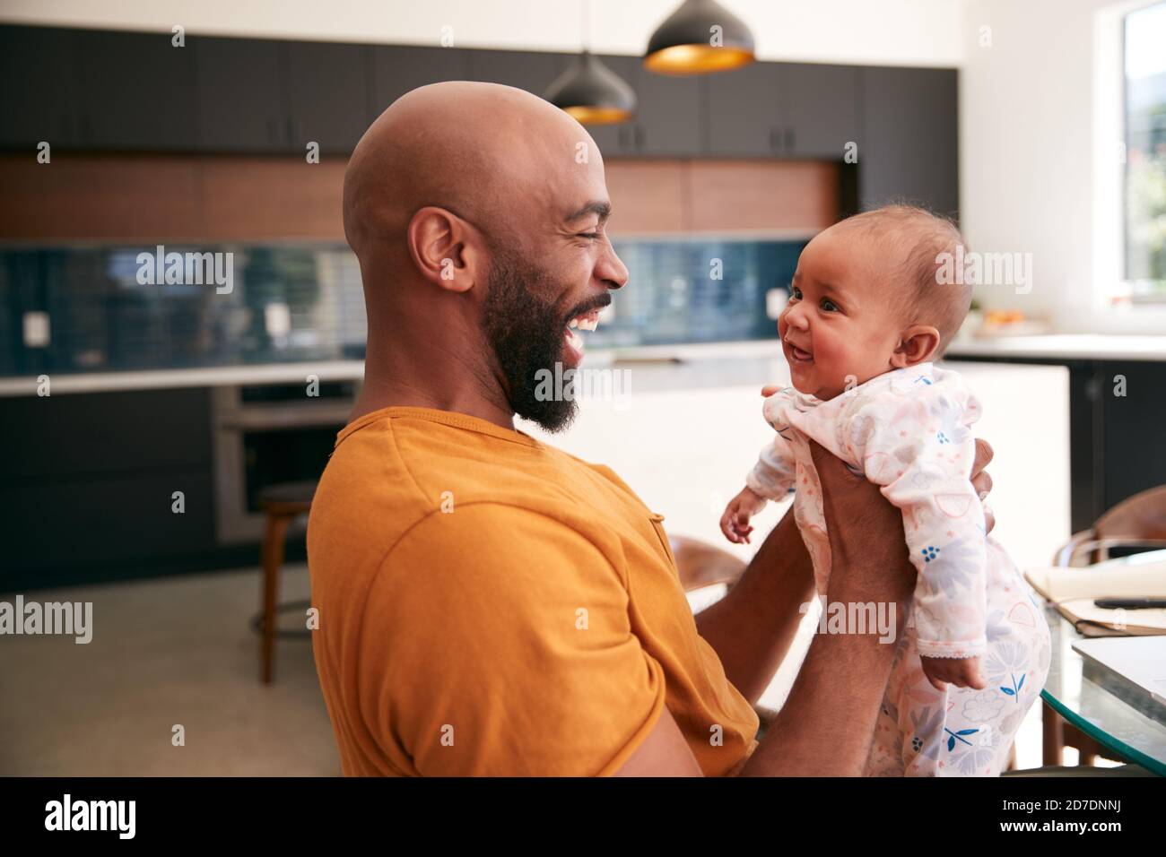 Smiling Stay At Home African American Father Cuddling And Playing With Baby Daughter Indoors At Home Stock Photo