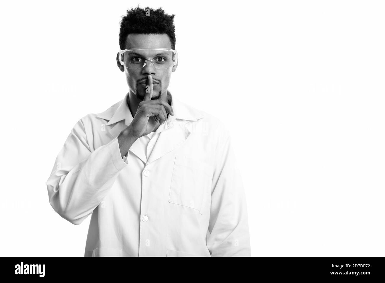 Studio shot of young African man doctor with finger on lips Stock Photo
