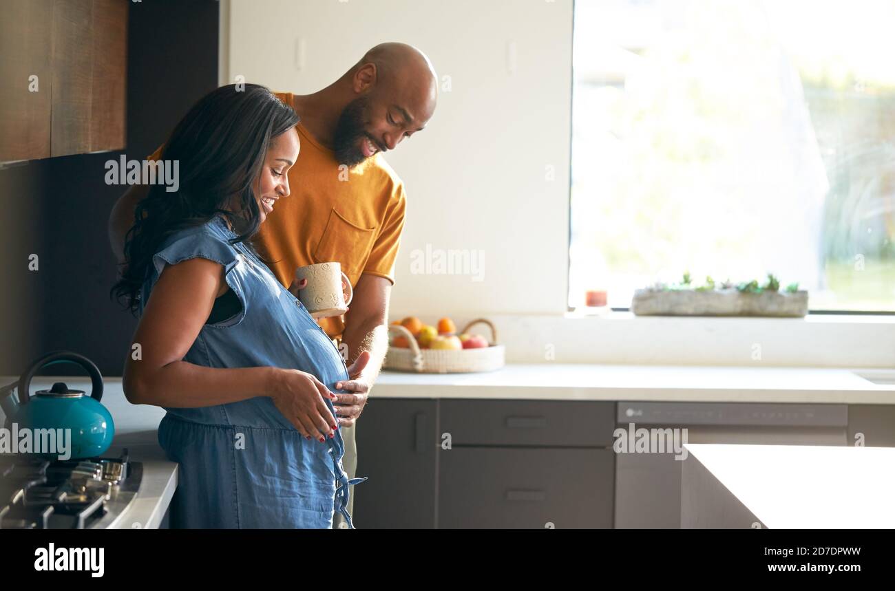 Loving African American Husband With Pregnant Wife At Home In Kitchen ...
