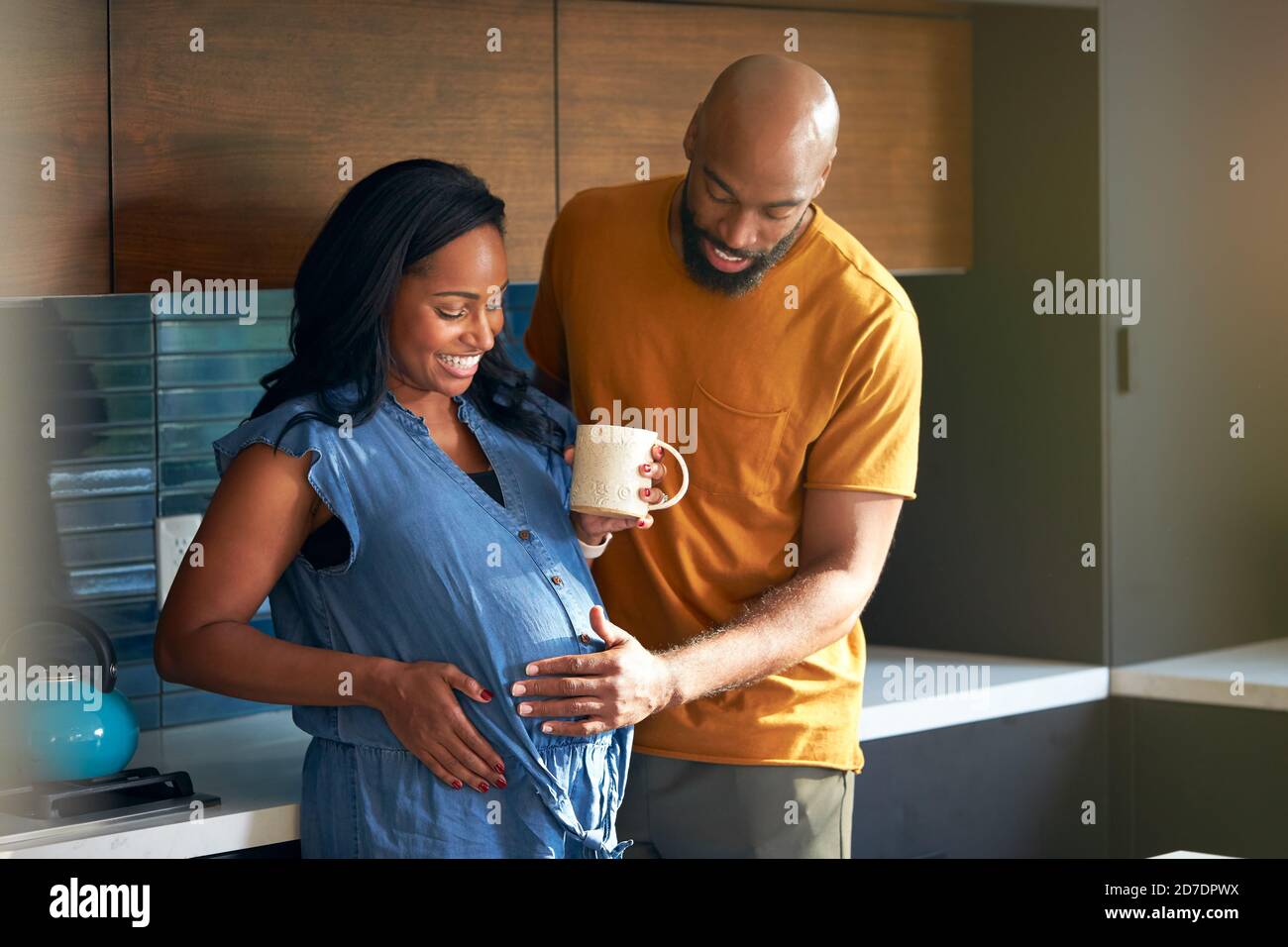 Loving African American Husband With Pregnant Wife At Home In Kitchen ...