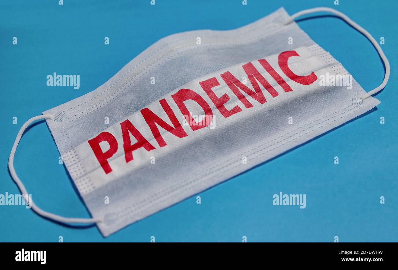 Medical face mask with PANDEMIC text on blue background. Concept of coronavirus quarantine. Stock Photo