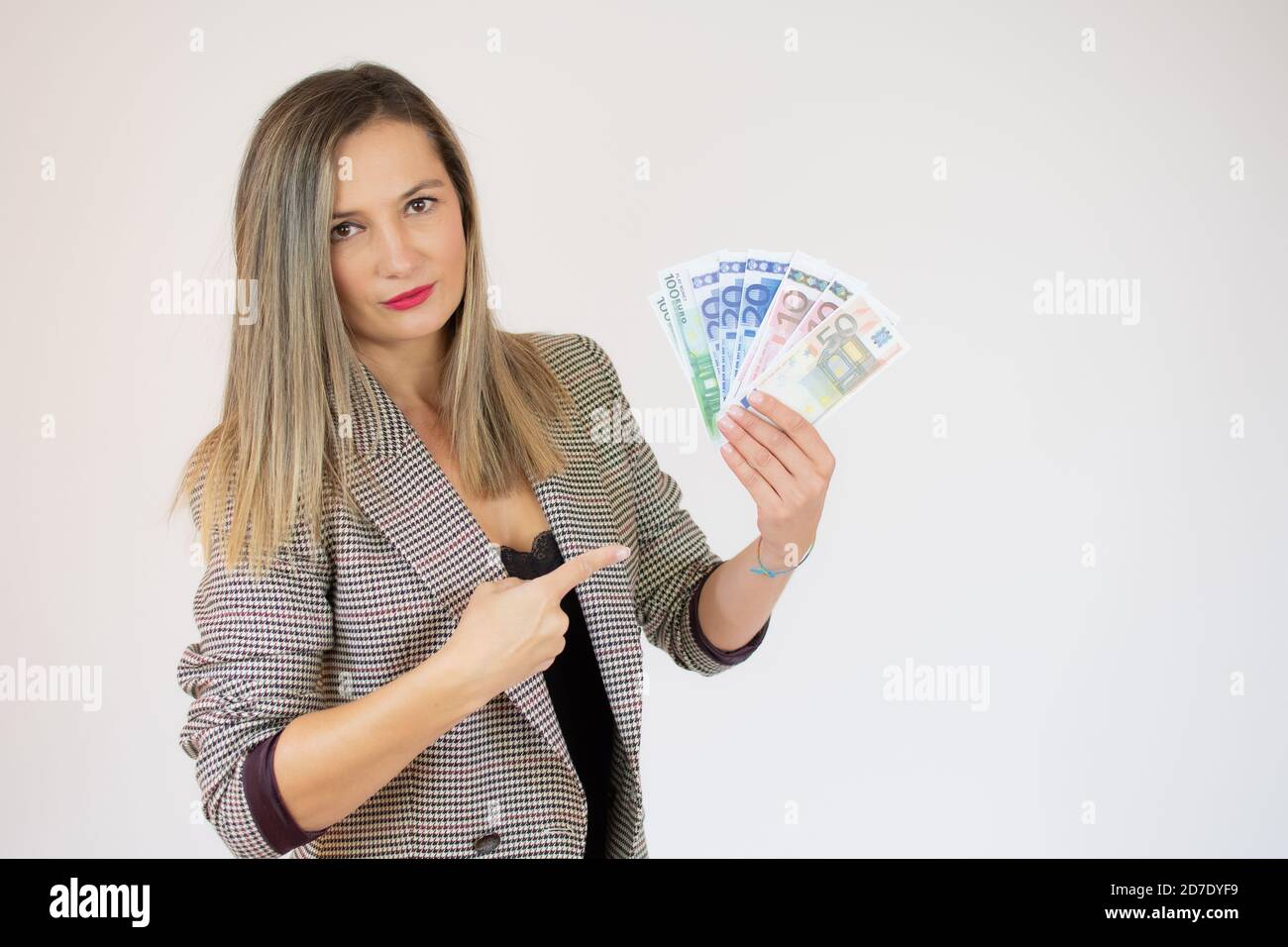 Portrait of a businesswoman pointing finger at bunch of money banknotes ...