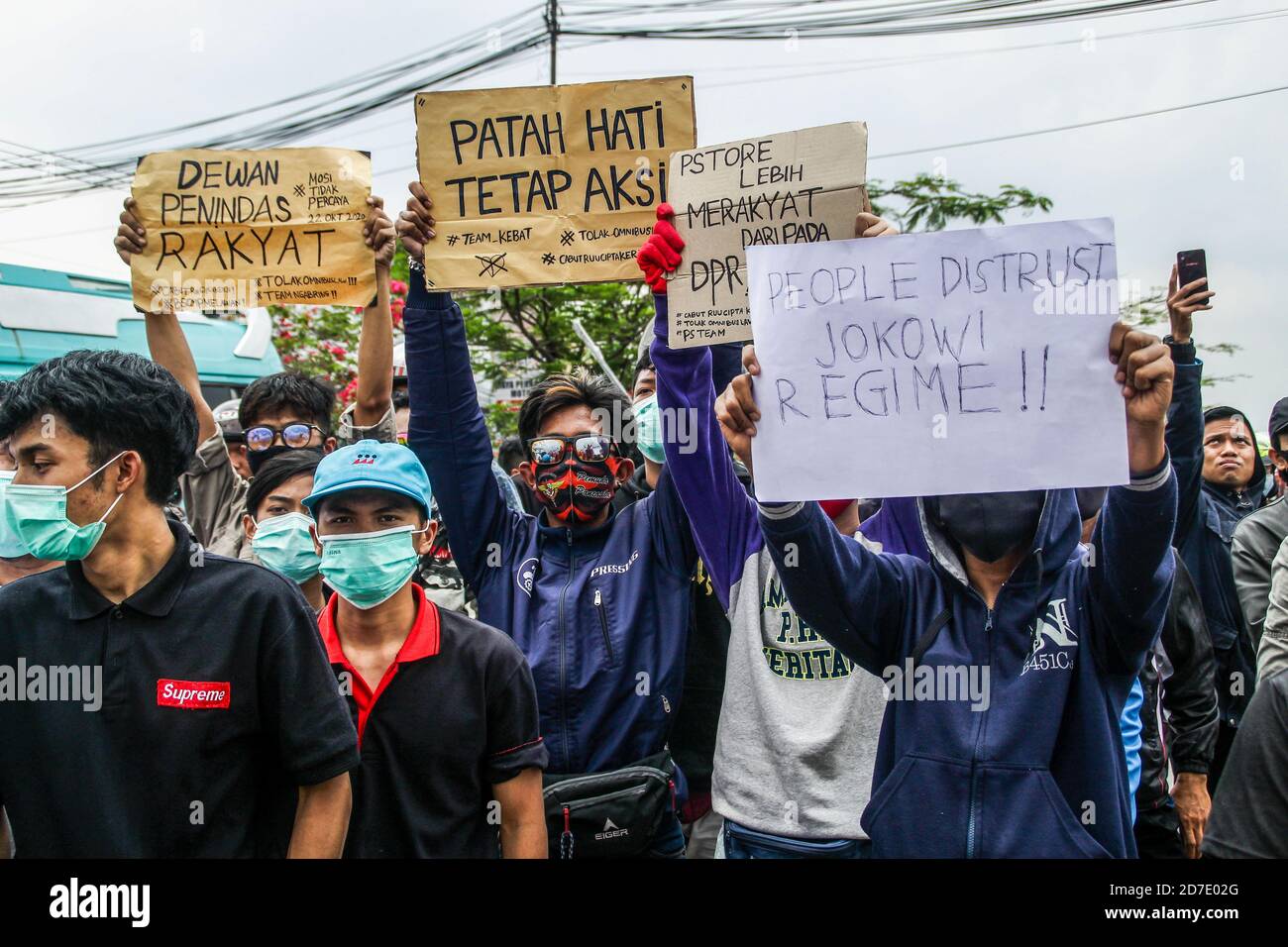 Protesters wearing facemask display   protest placards outside the factory during protest in Rancaekek. Thousands protest against a controversial law 'omnibus' that was passed by Parliament. The new law aims to create jobs and raise investment by reducing regulatory requirements for business permits and land acquisition processes. Many fear, the new law will harm labour rights and indigenous land rights. Stock Photo