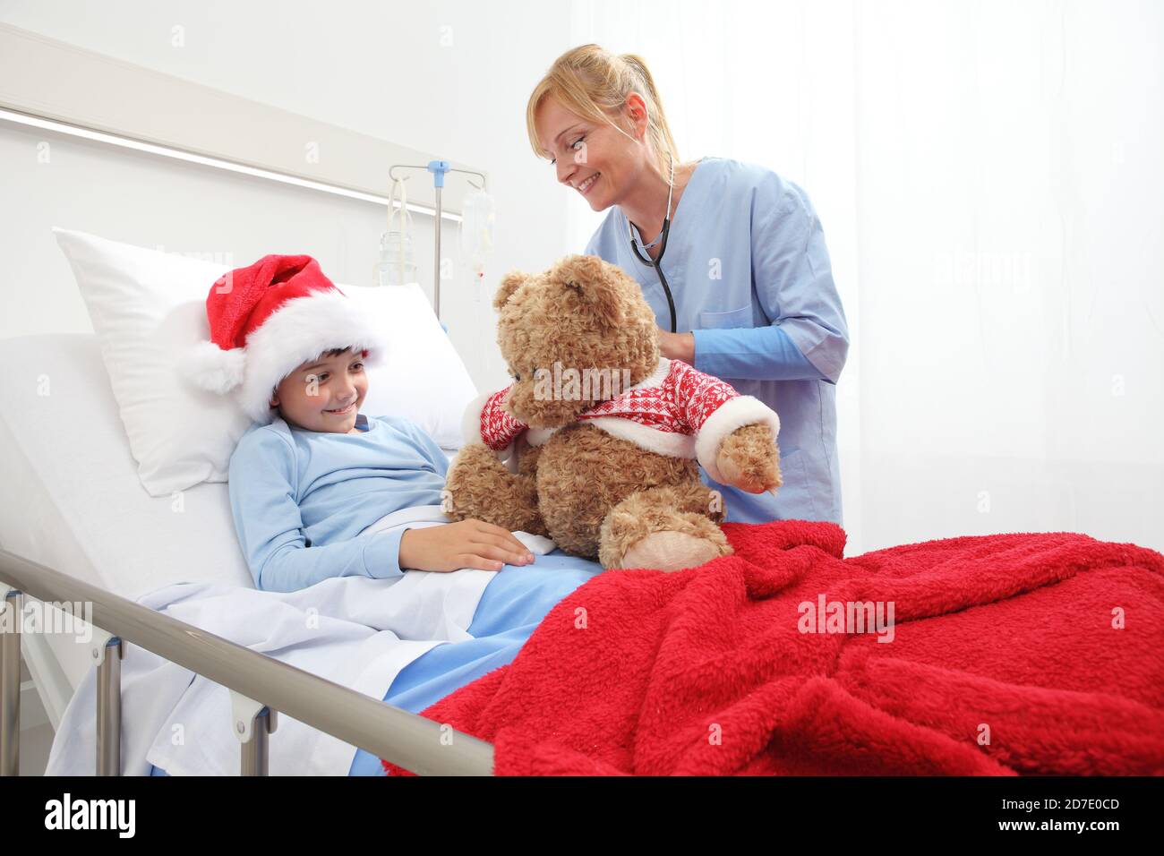 Christmas holiday in hospital happy child lying in bed with Santa Claus ...
