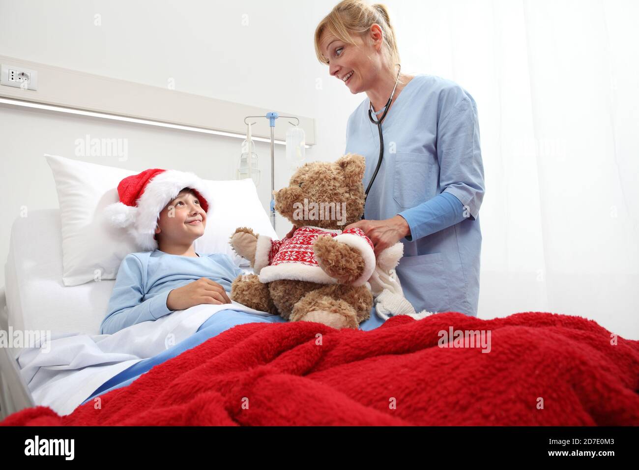 Christmas holiday in hospital happy child lying in bed with Santa Claus ...
