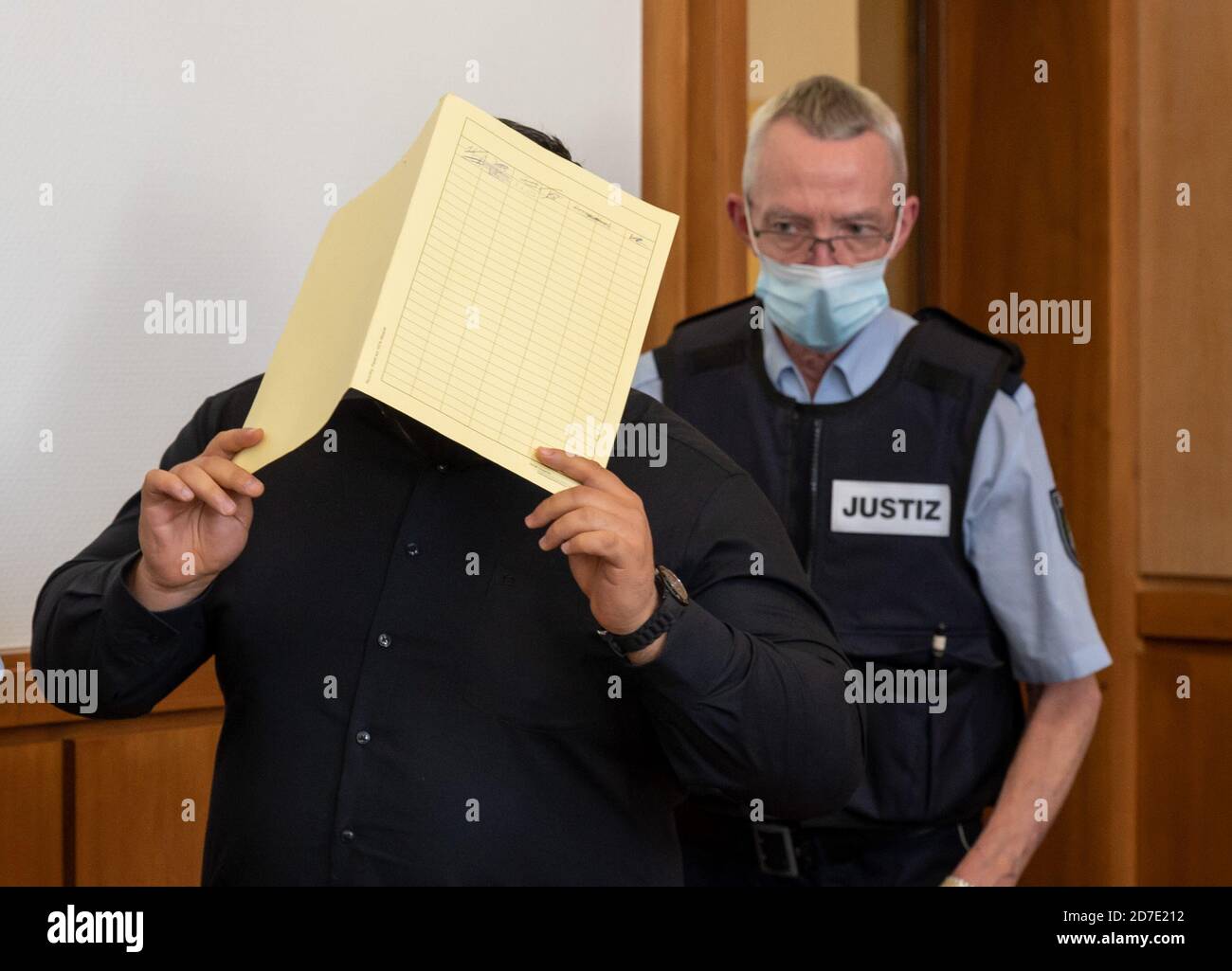 Hagen, Germany. 22nd Oct, 2020. One of the accused is accompanied by a justice official to the hall of the regional court. Five suspected members of the biker group 'Bandidos' are accused of two attacks on members of the hostile 'Hells Angel'. Credit: Bernd Thissen/dpa/Alamy Live News Stock Photo