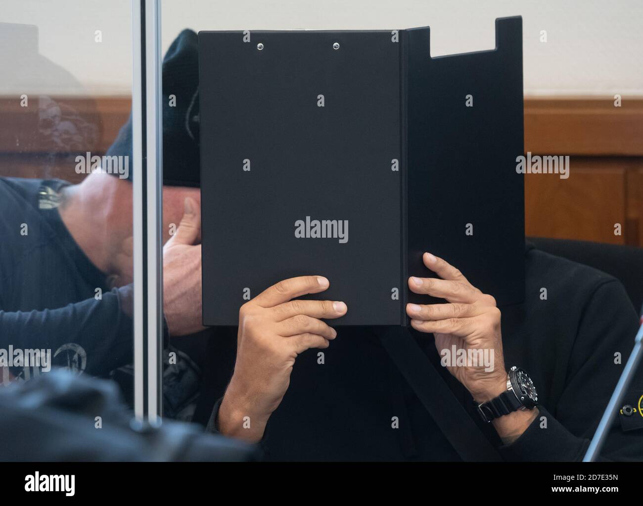 Hagen, Germany. 22nd Oct, 2020. Two of the accused are talking behind a folder in the hall of the regional court. Five suspected members of the biker group 'Bandidos' are accused of two attacks on members of the hostile 'Hells Angel'. Credit: Bernd Thissen/dpa/Alamy Live News Stock Photo