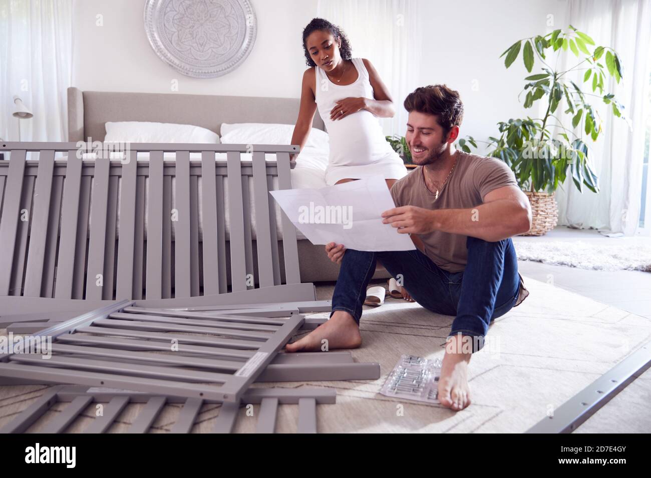 Couple With Pregnant Woman Looking At Instructions For Self Assembly