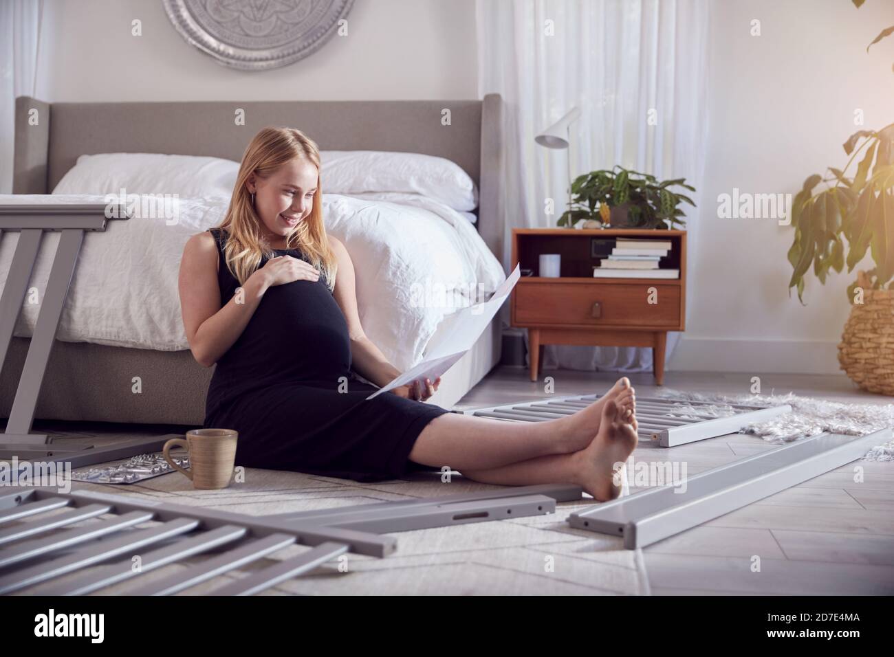 Pregnant Mother To Be Looking At Instructions For Self Assembly Baby