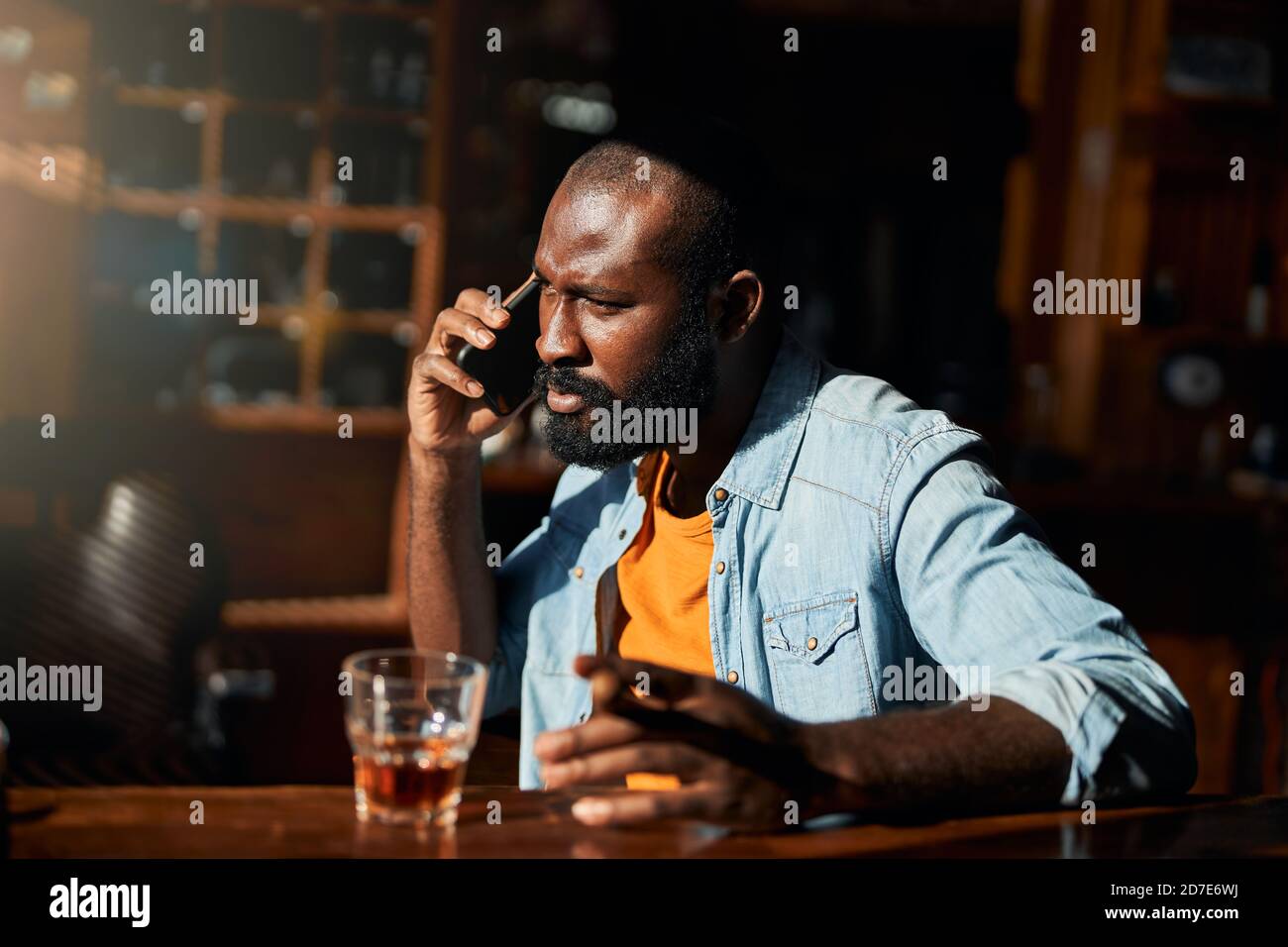 Handsome Afro American man with cigar talking on cellphone Stock Photo